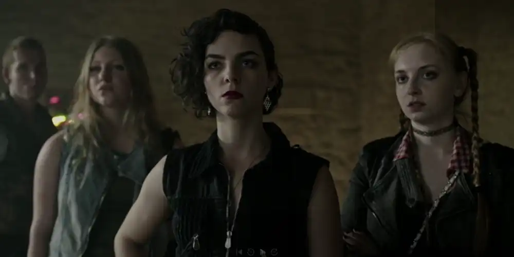 Drei junge Personen in einer Bar, die im Stil der neuen deutschen Welle gekleidet sind. In A Cure for Wellness.